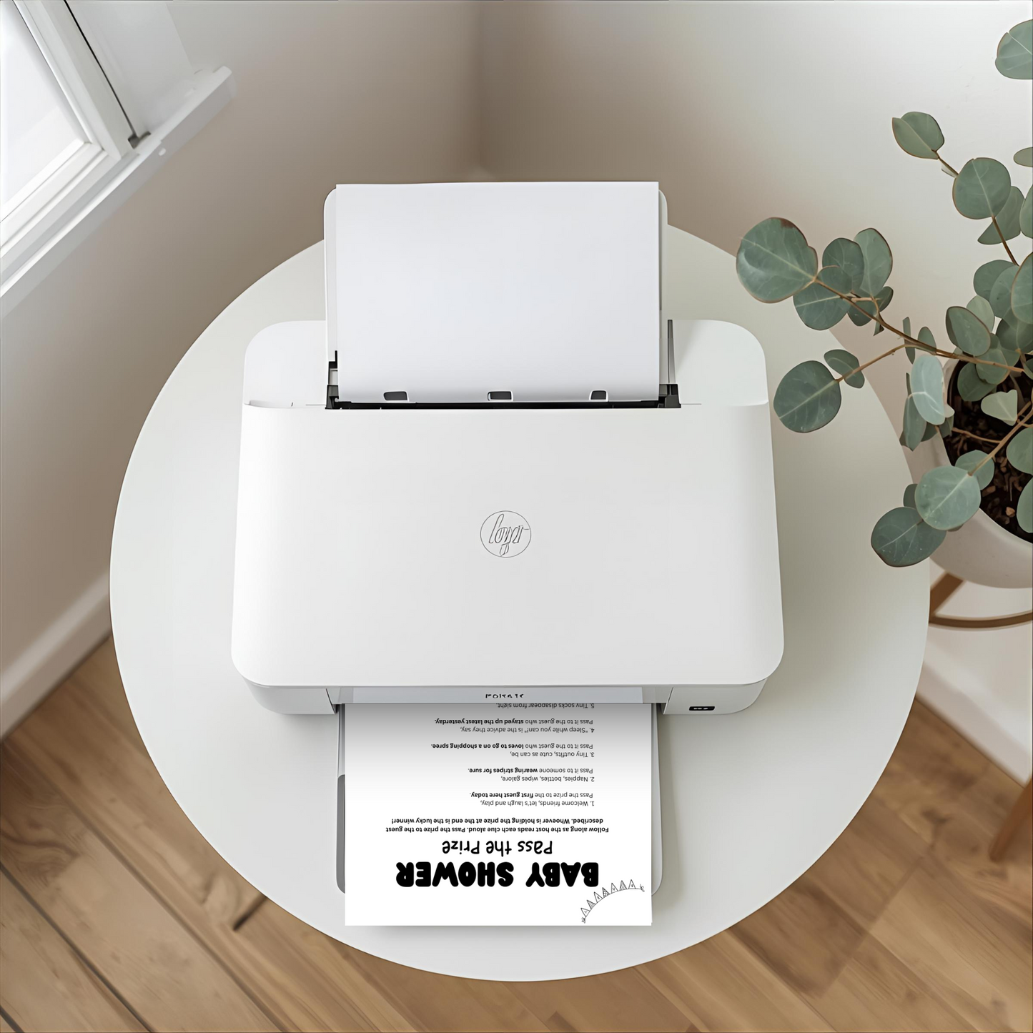 A white HP mini printer sits on a round white table in a bright room, with a sheet of paper inserted at the top and another printed sheet coming out. A potted eucalyptus plant is visible on the right, and a window and wood floor are in the background.