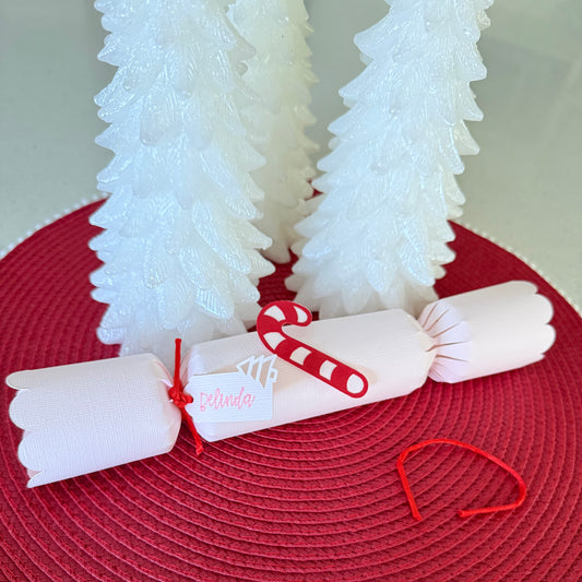 Decorative Christmas cracker with candy cane and white trees on a red surface