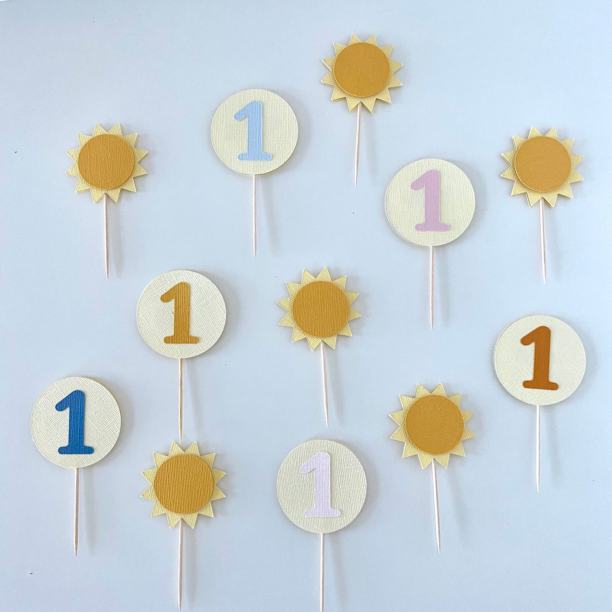 Decorative cupcake toppers with numbers on sticks against a white background