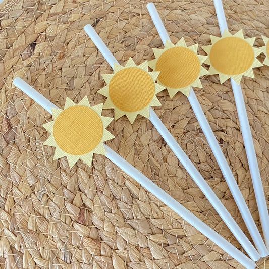 Four white straws with sun-shaped ends on a woven mat background
