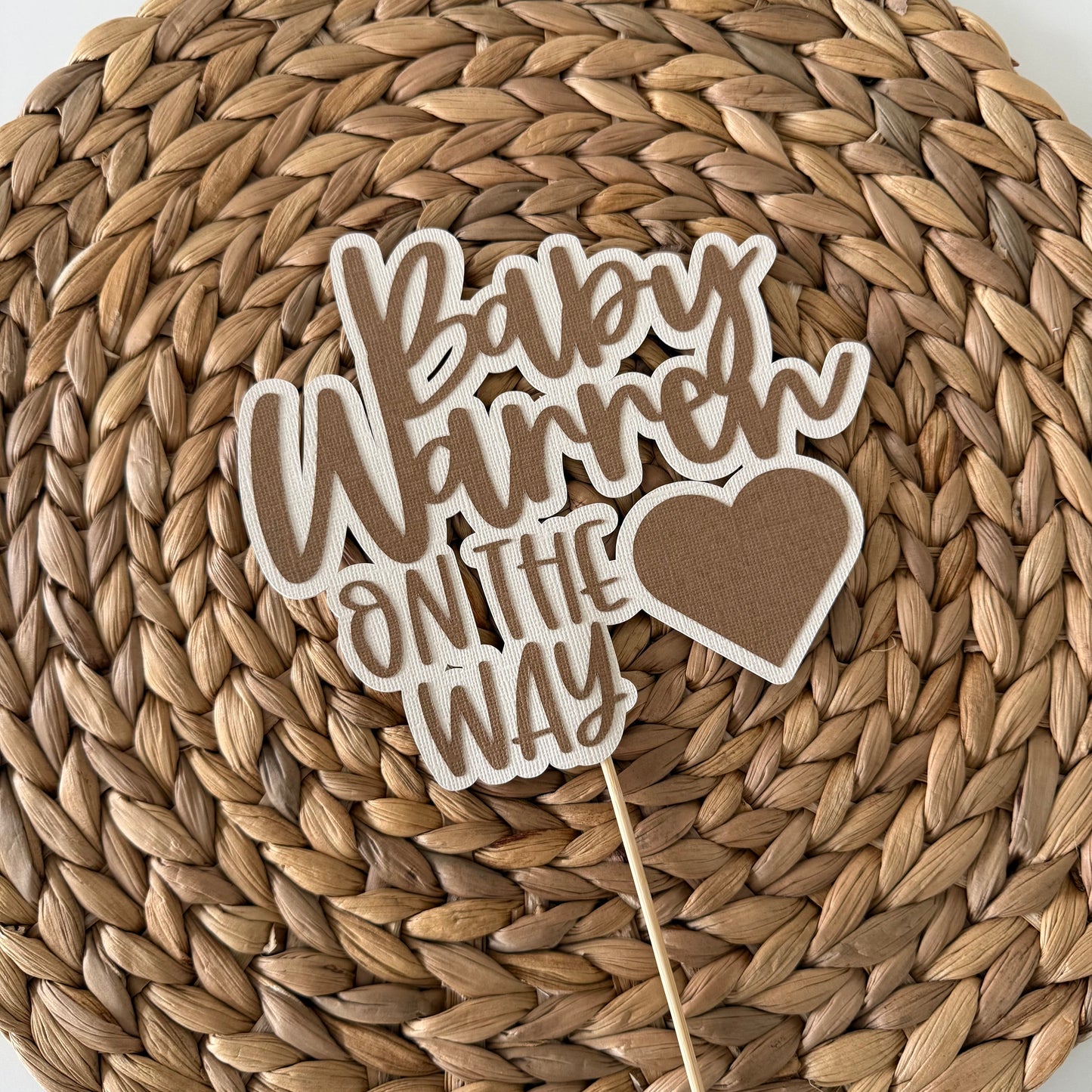 Baby shower decoration with 'Baby on the way' text on a woven mat