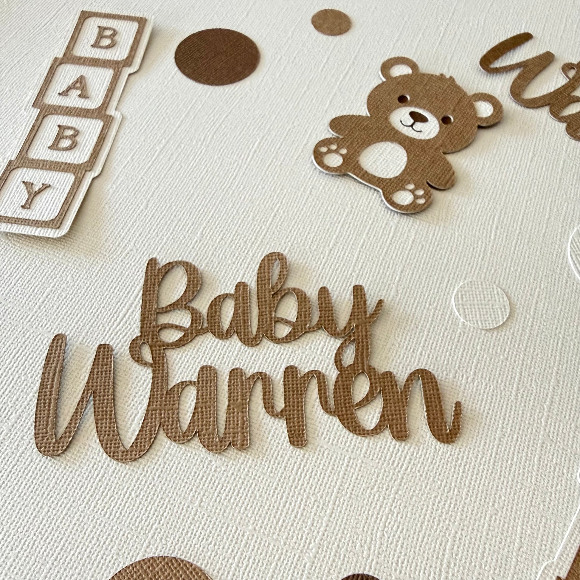 Baby surname name with teddy bear and baby blocks on a textured surface