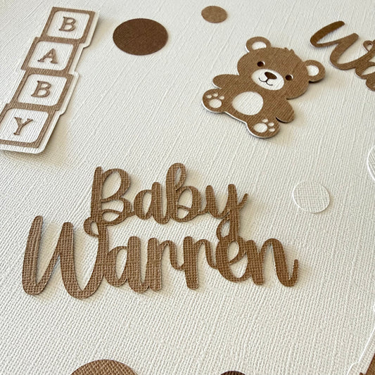 Baby surname name with teddy bear and baby blocks on a textured surface