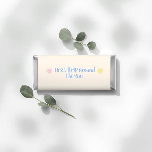 Chocolate bar with 'First Trip Around the Sun' text on a white background with eucalyptus leaves.