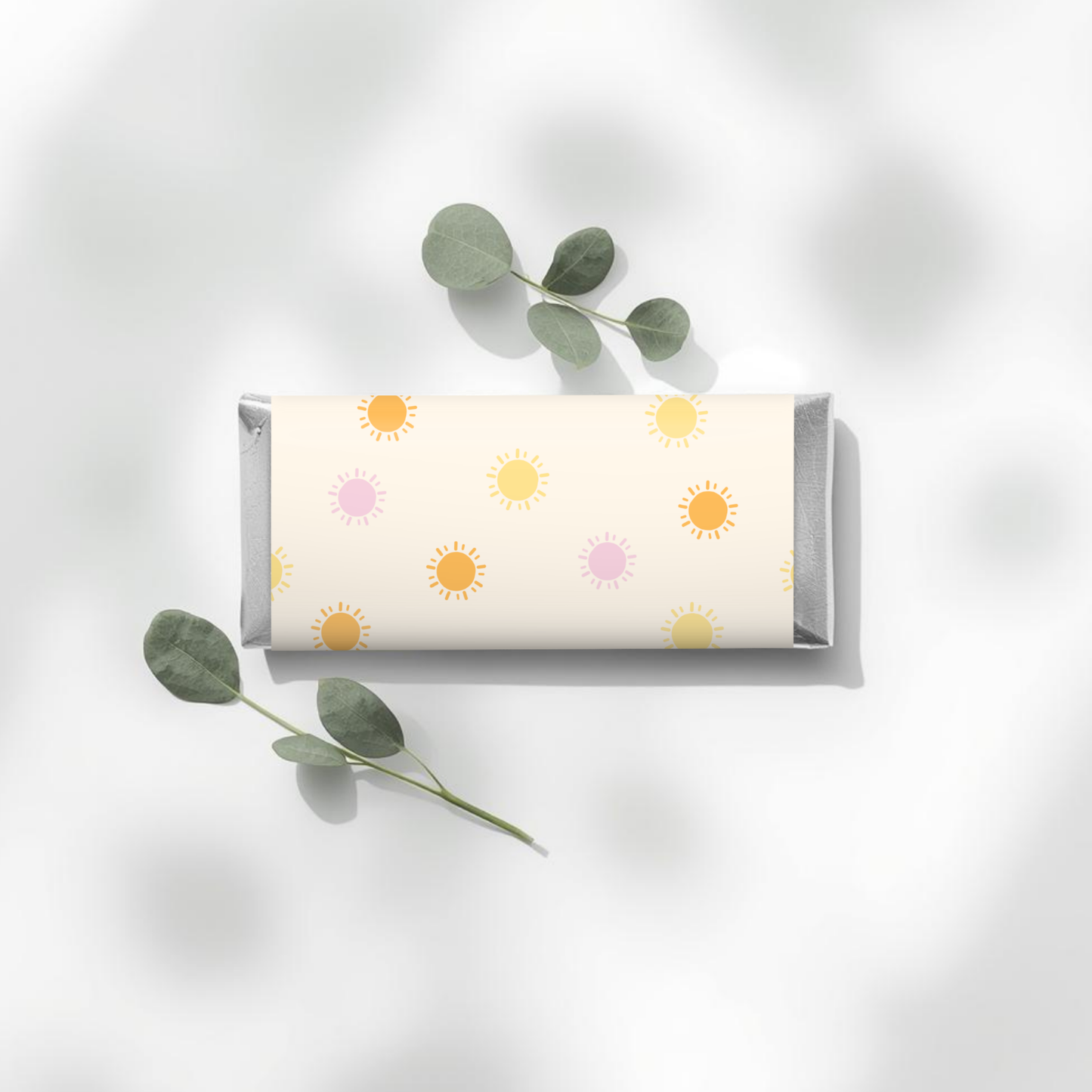 Chocolate bar wrapper Aldi with a sun pattern on a white background with eucalyptus leaves.