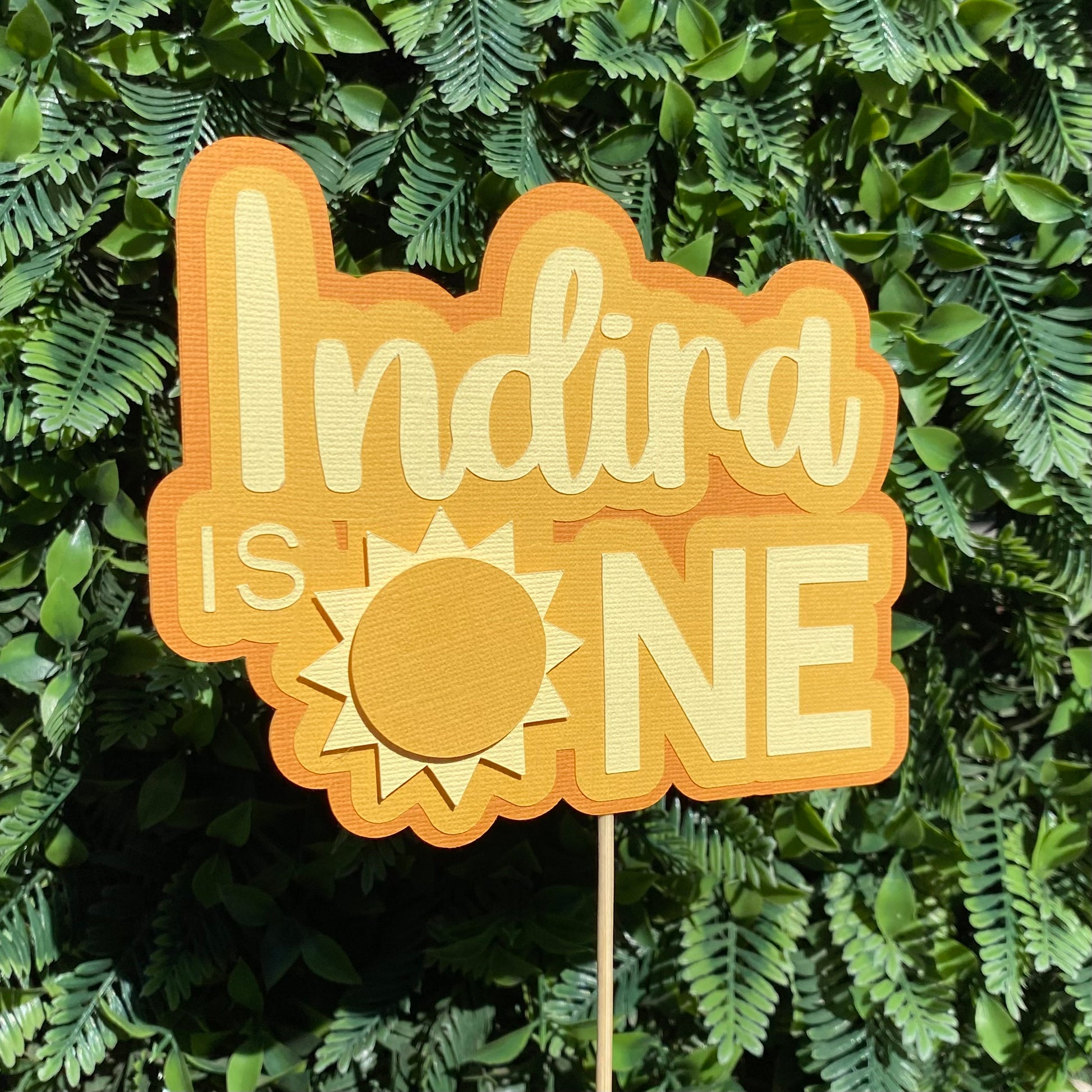 Decorative sign with 'Indira is ONE' on a green leafy background