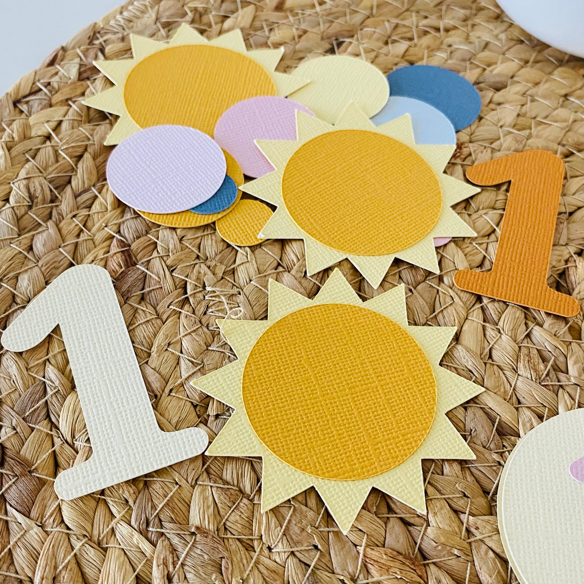 Colorful sun-shaped and number-shaped paper cutouts on a woven surface