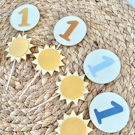 Decorative cupcake toppers with number '1' on a woven surface
