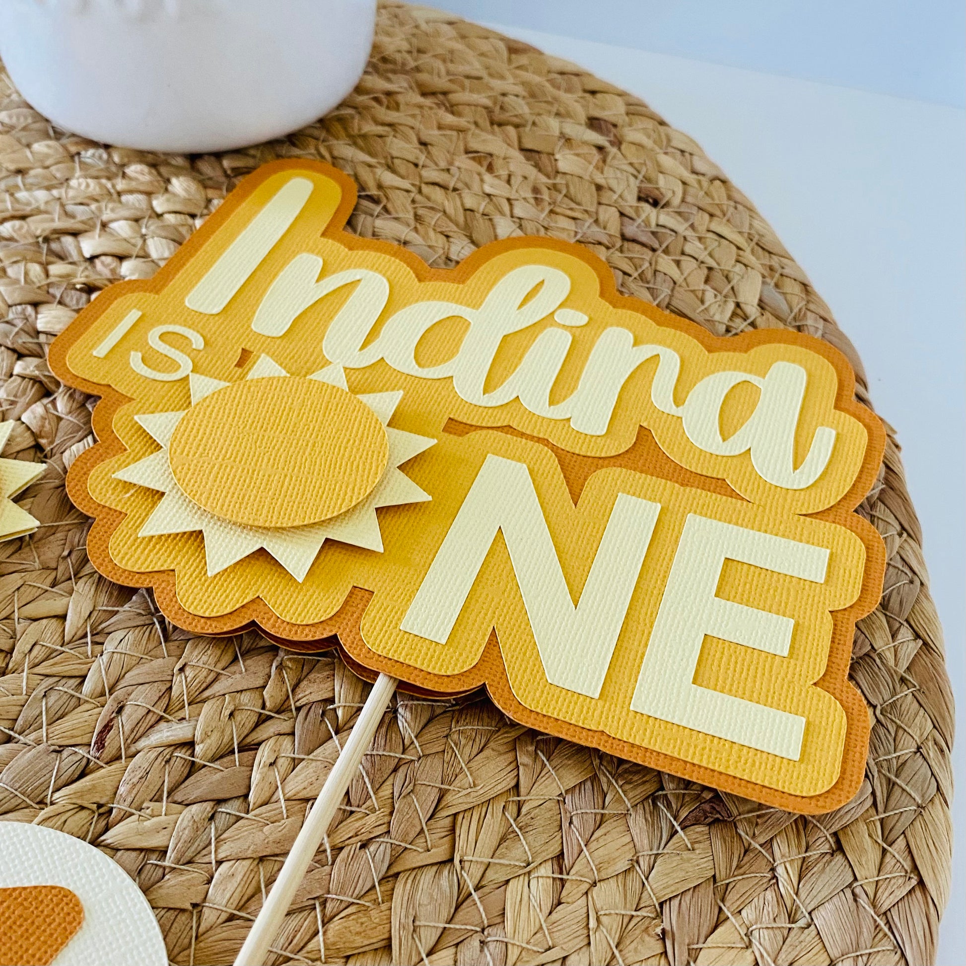 Decorative sign with 'Indira is One' text on a woven surface