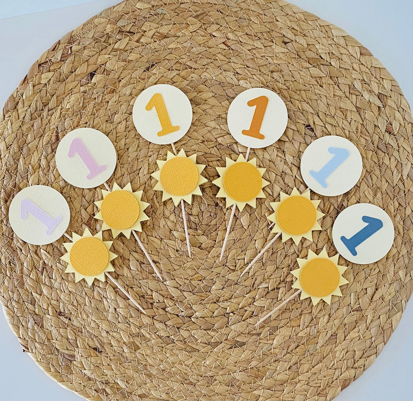Decorative cake toppers with number '1' on a woven mat