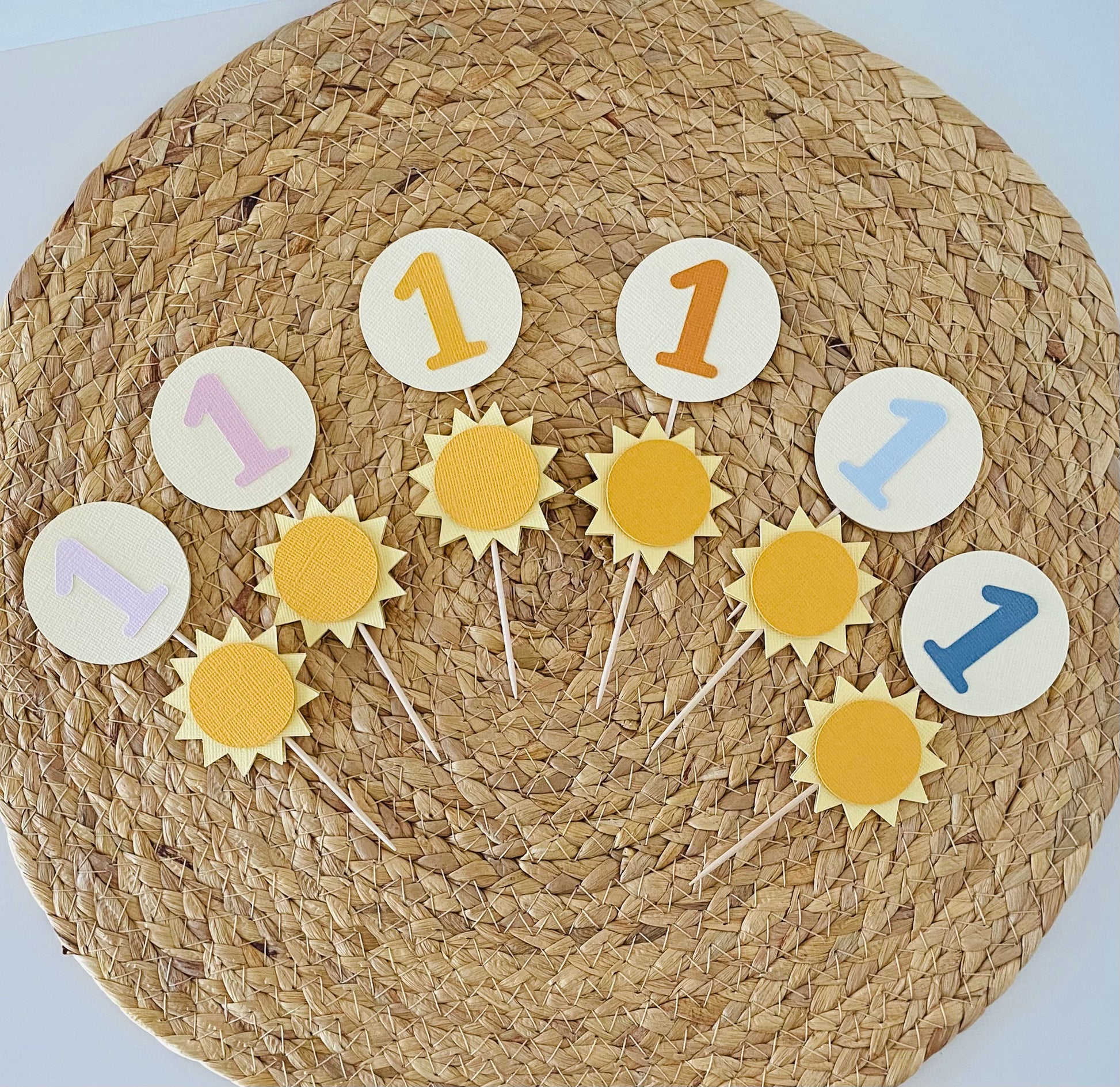 Decorative cake toppers with number '1' on a woven mat