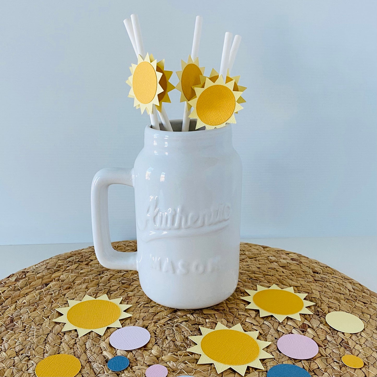 White Mason jar with yellow sun-shaped straws on a textured surface