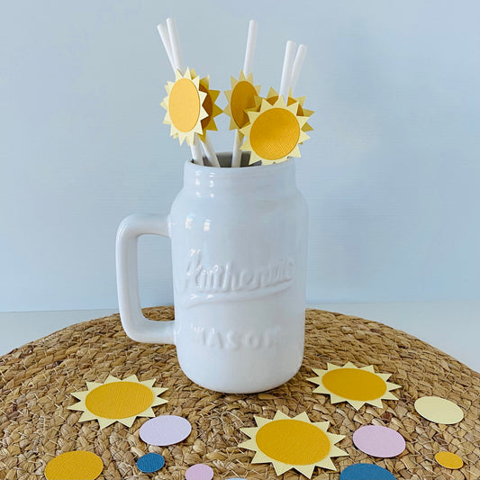 White Mason jar with yellow sun-shaped straws on a textured surface