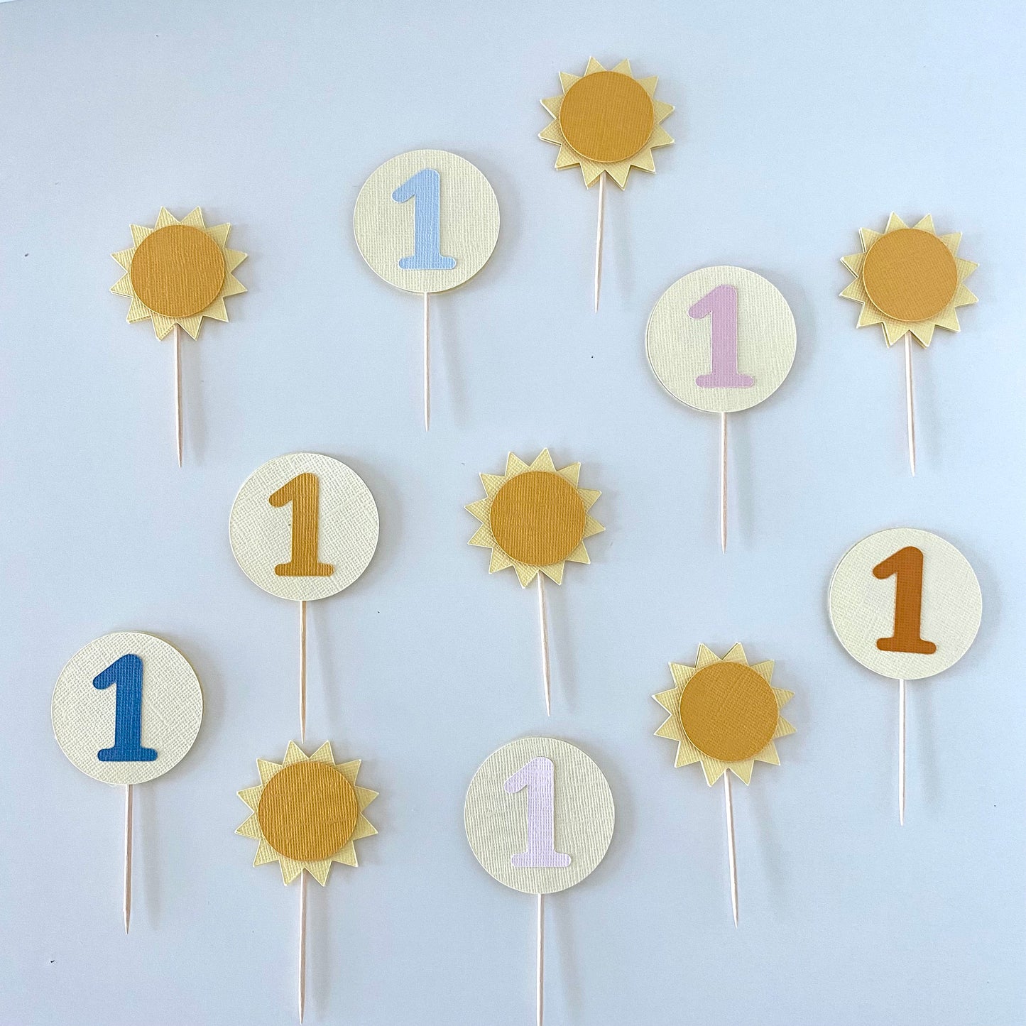 Decorative cupcake toppers with numbers on sticks against a white background