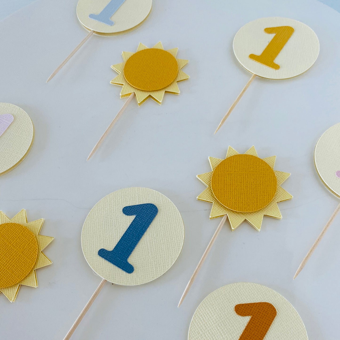 Decorative items with numbers and sun designs on sticks against a light background