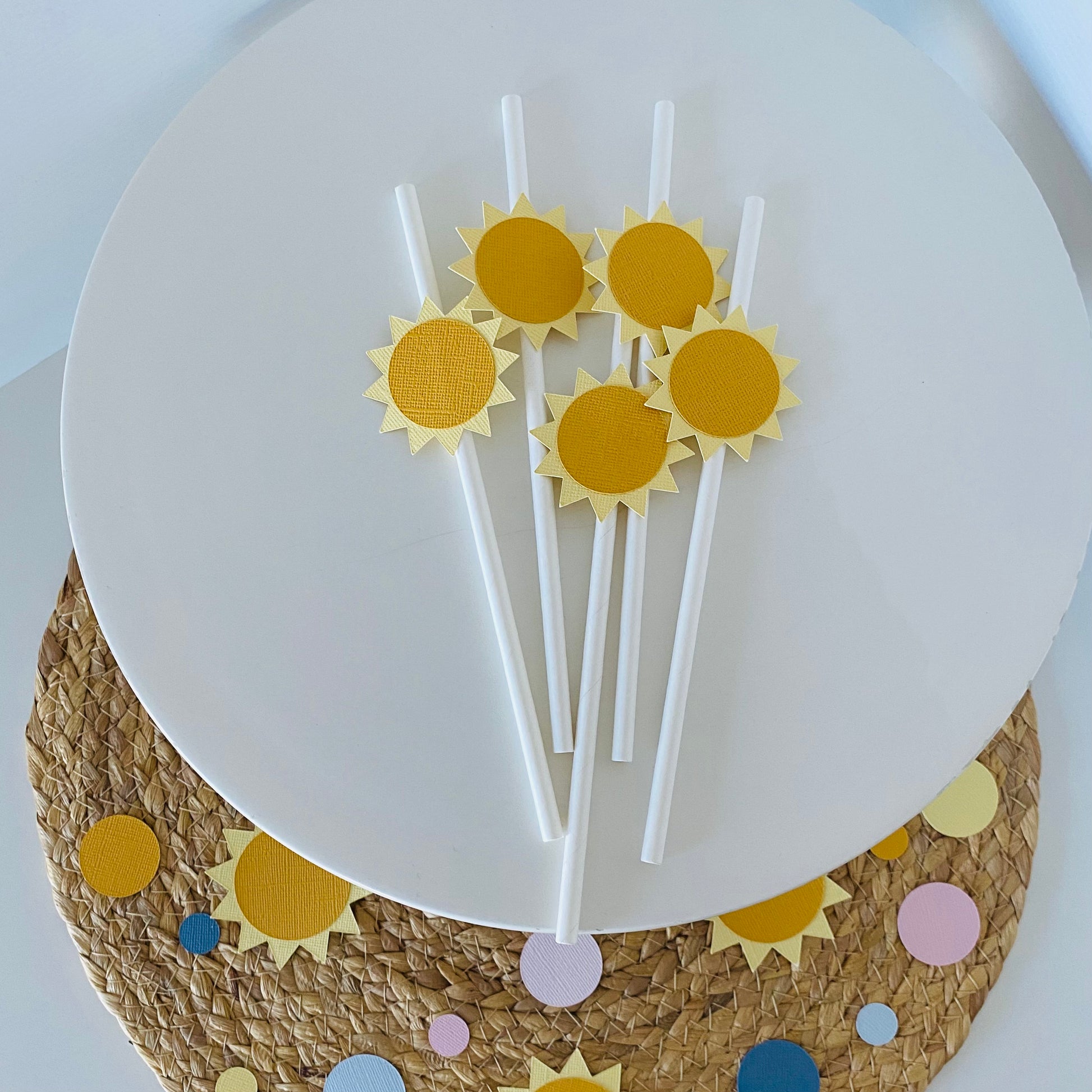 Sun-shaped paper straws on a white plate with a decorative mat underneath.